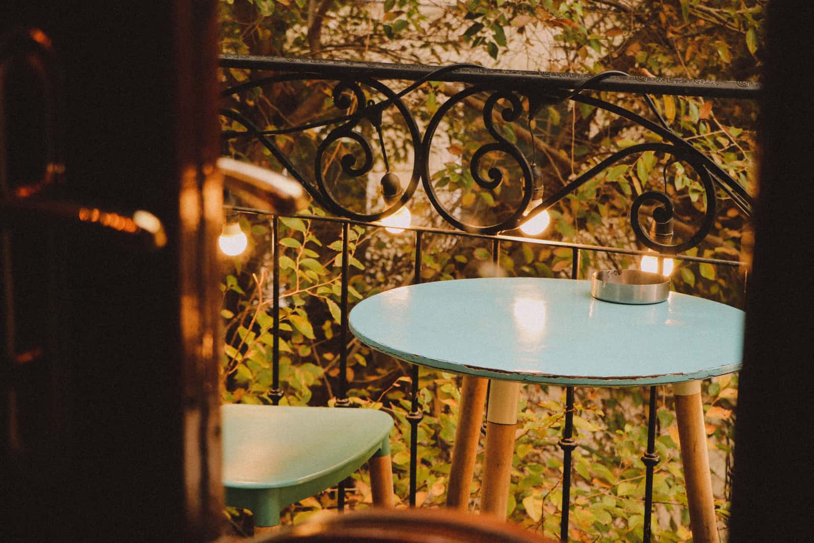 A small apartment balcony lit with string lights and a lantern