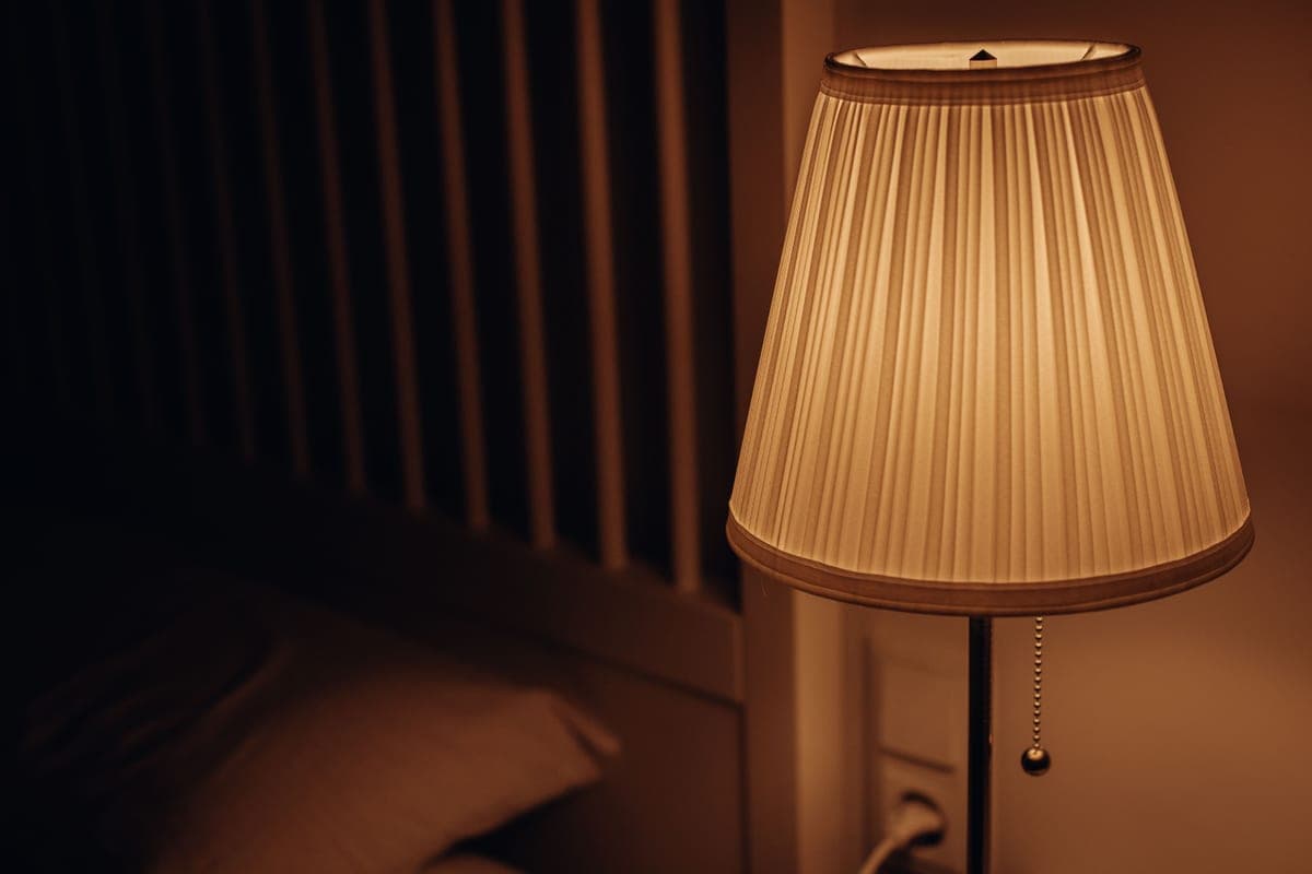 A bedroom at night lit by a warm bedside lamp with no ceiling fixture