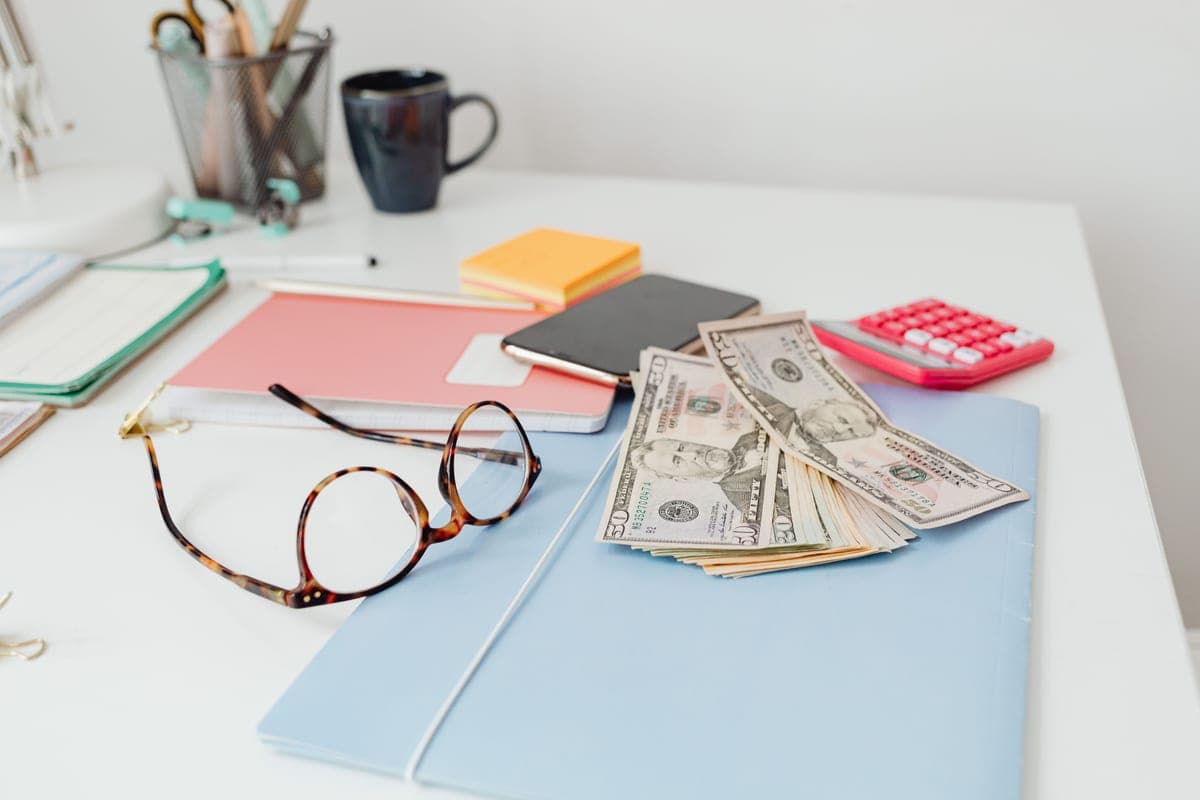 A calculator and notebook beside a lit lamp