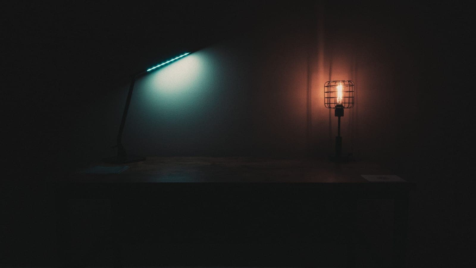 A dorm room desk lit by a small lamp in the evening