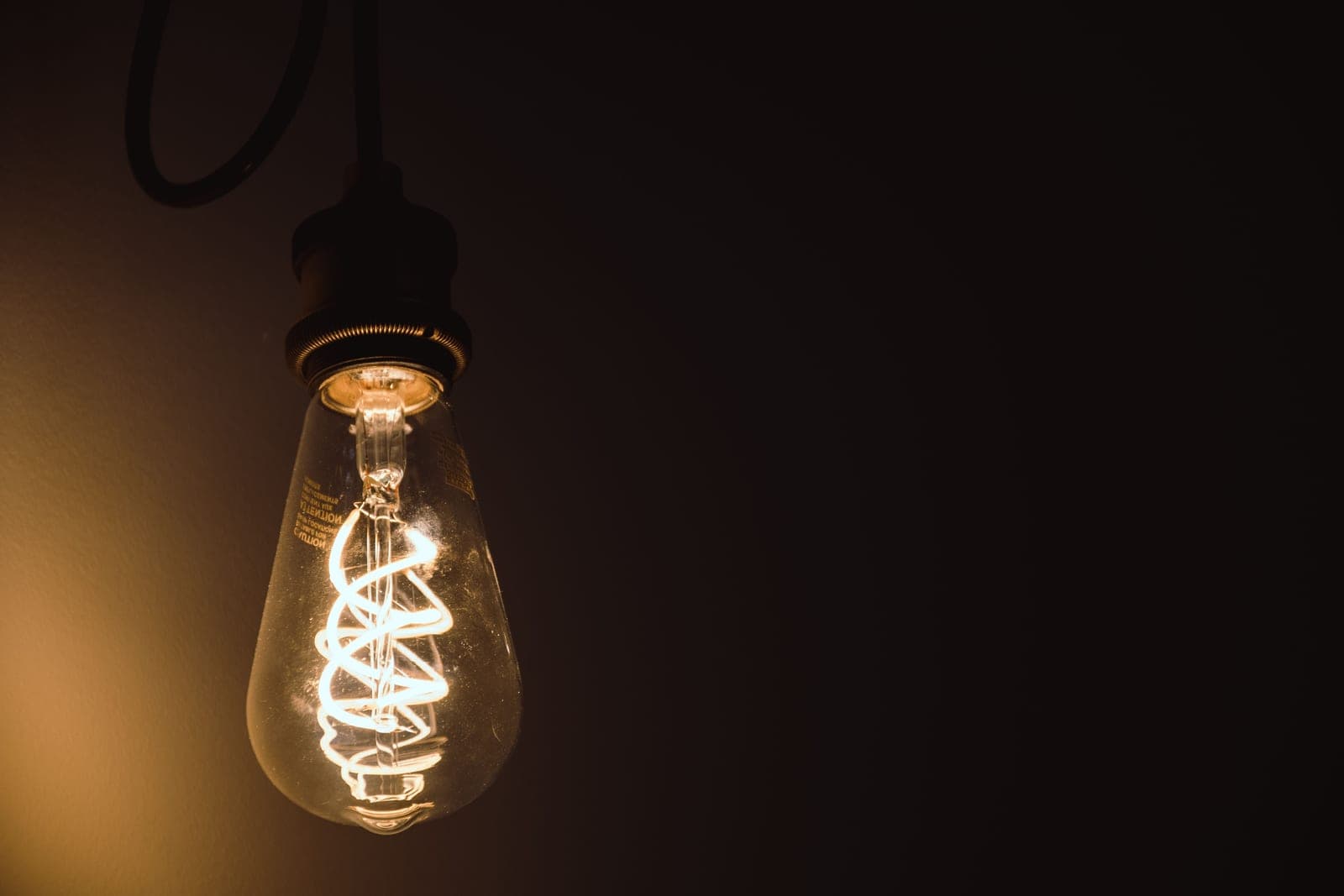 An amber filament LED bulb glowing in an exposed pendant fitting