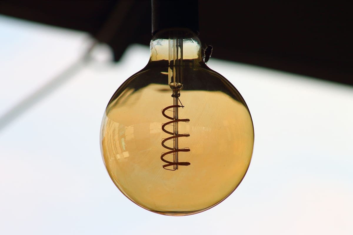 A warm filament-style LED bulb glowing against a dark background