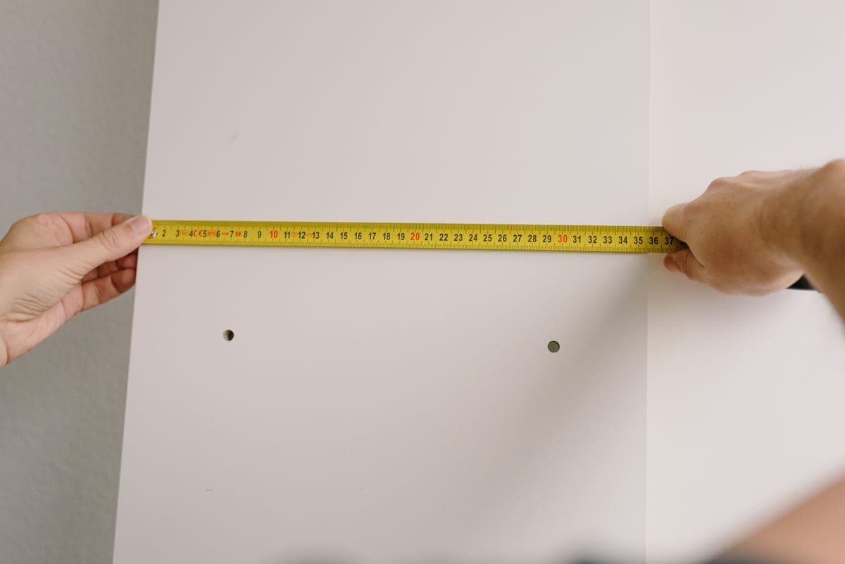 A tape measure held under a kitchen wall cabinet