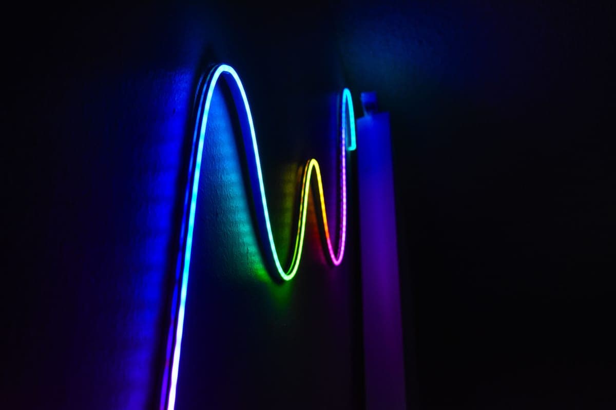 Hands pressing a light strip into place under a kitchen cabinet