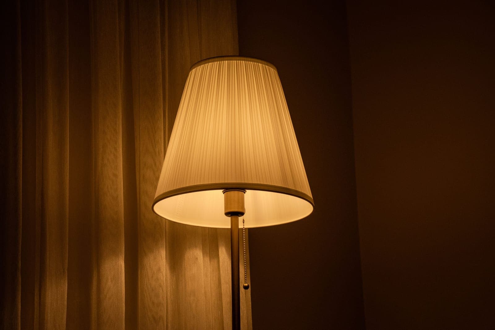 A fabric drum shade on a table lamp with light spilling up and down
