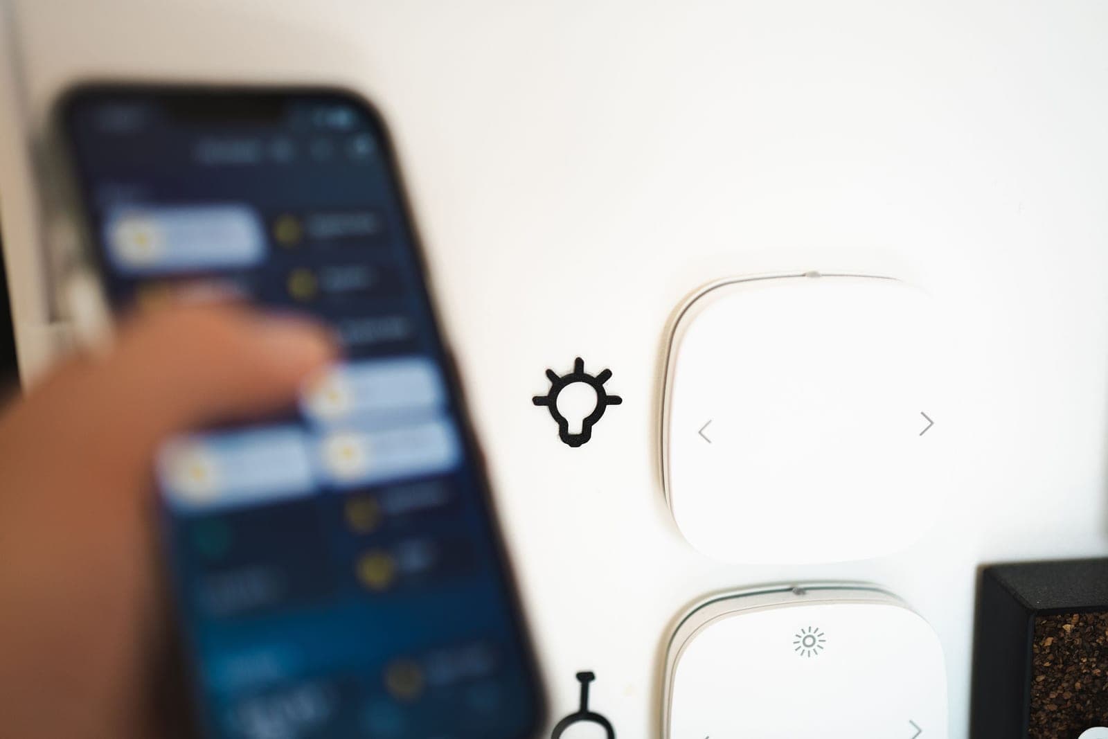 A wall dimmer and a wireless remote beside a warmly lit room