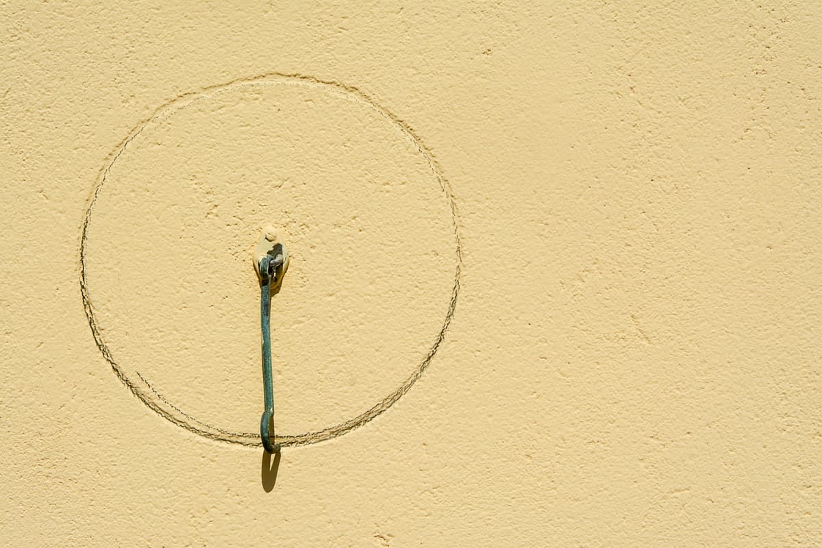 An adhesive hook mounted on a plain painted wall
