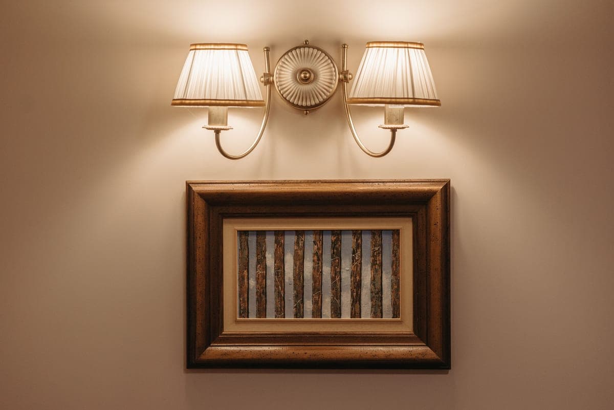 A framed picture on a wall lit from above