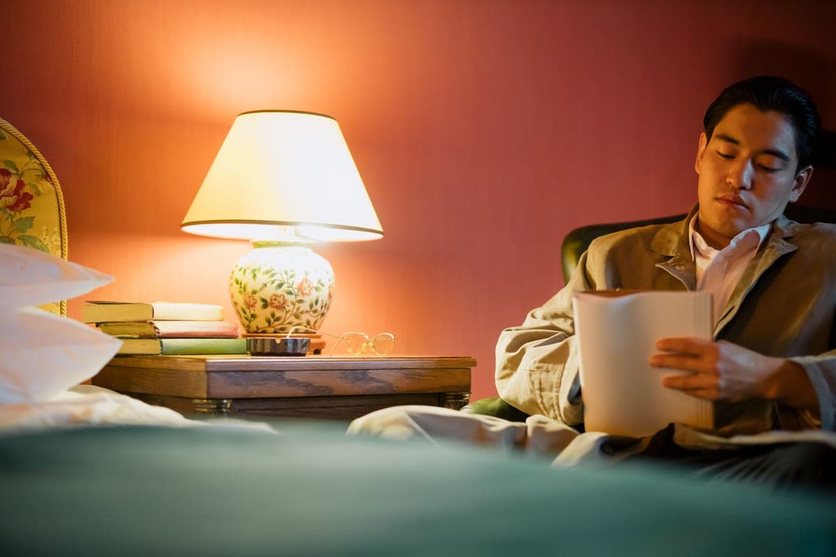 A reading lamp beside an armchair with an open book