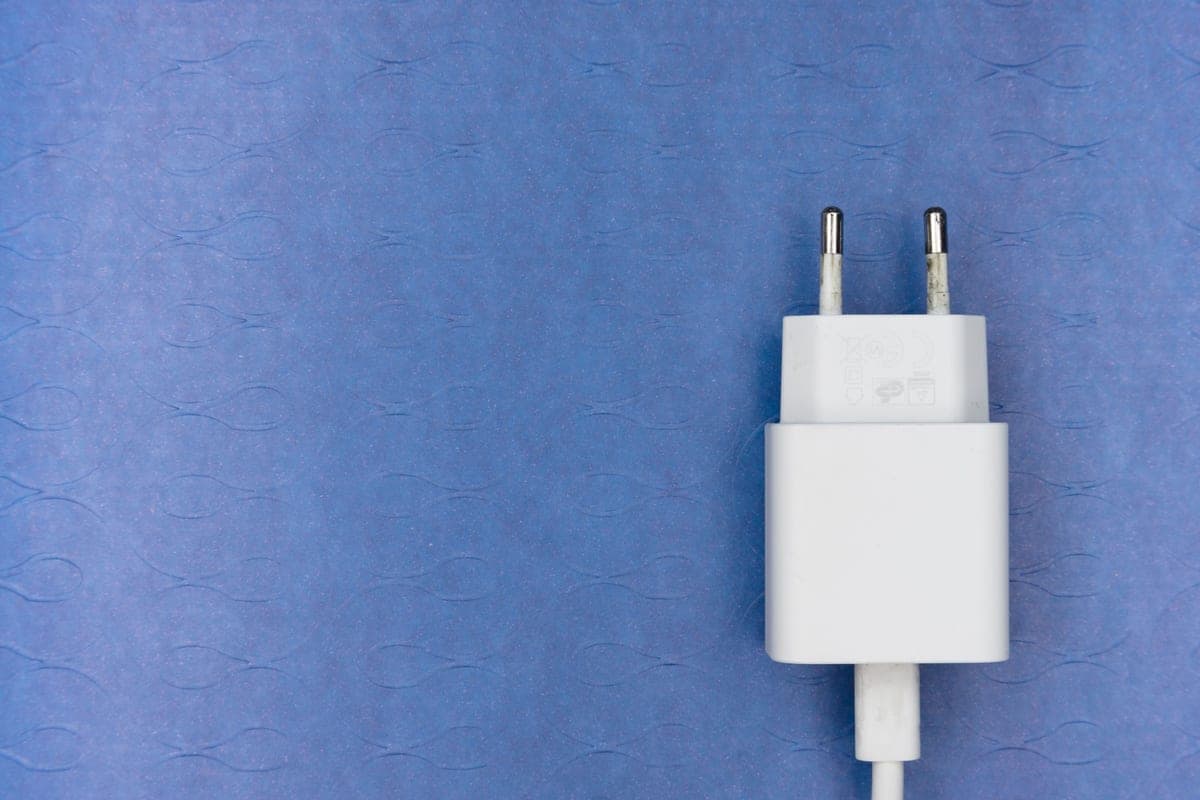 A plug adapter in a wall outlet behind a lamp