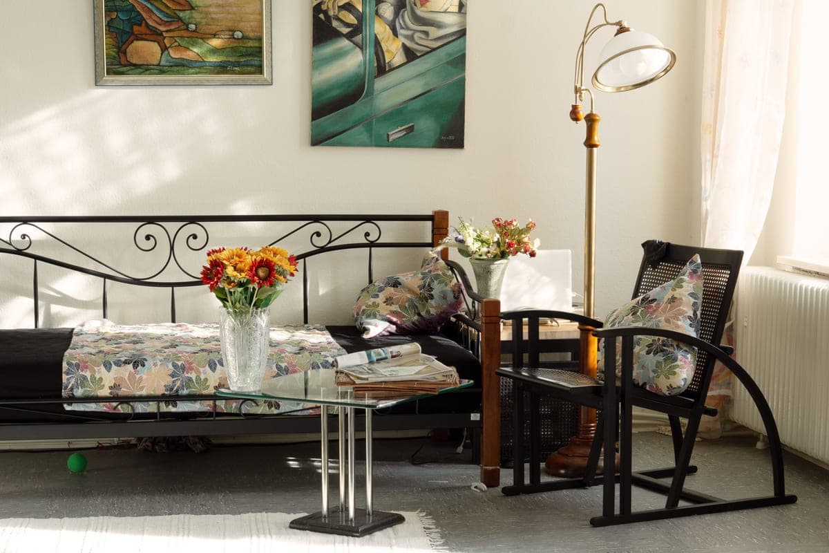 An apartment living room with a lamp lit and a phone on the arm of a sofa