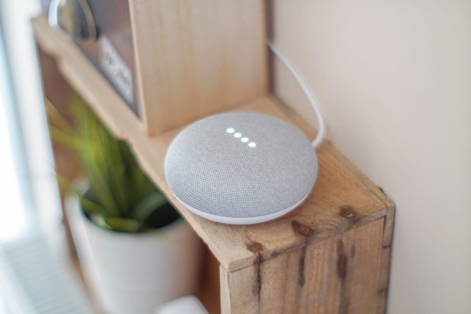 A smart speaker on a shelf beside a lamp