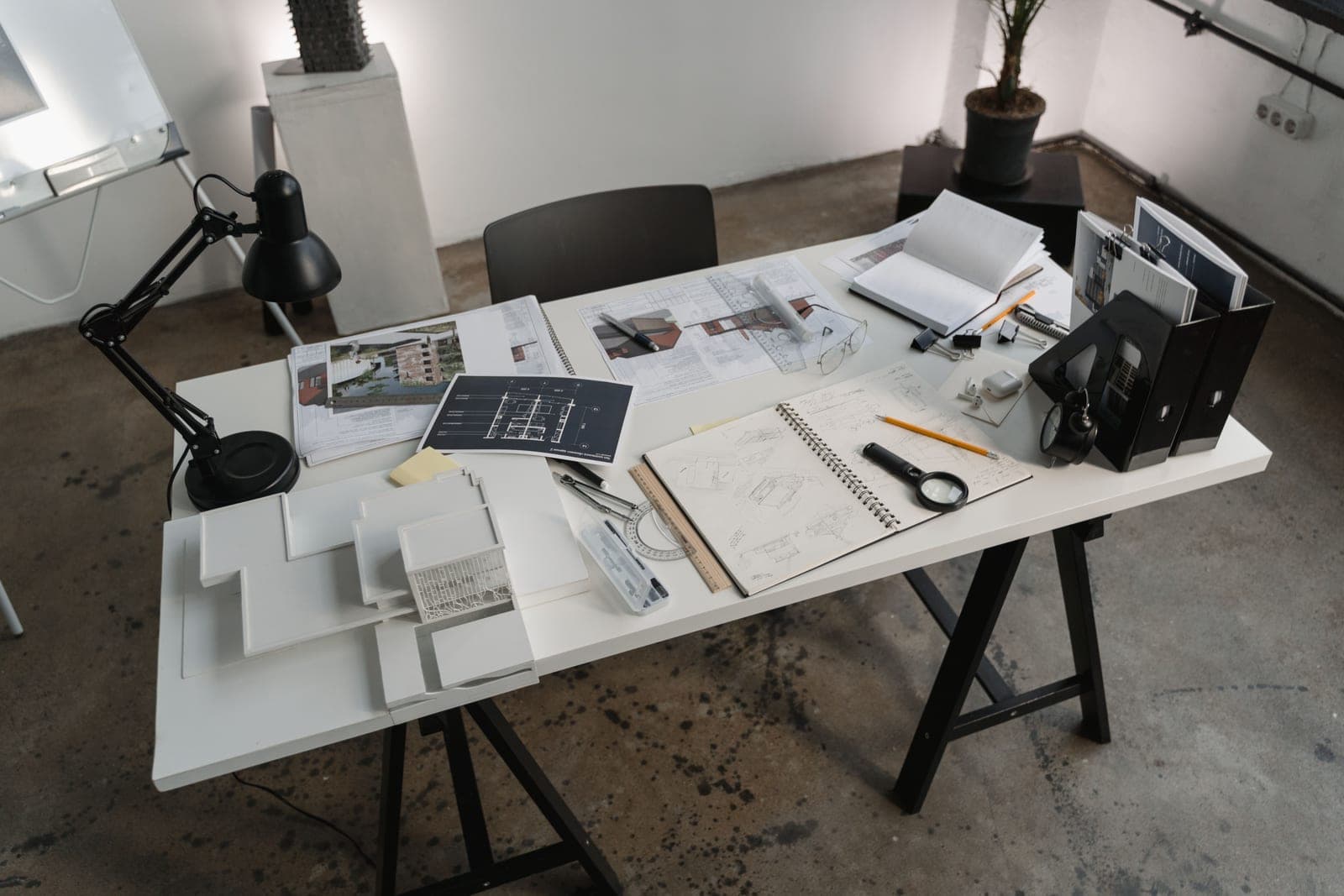 A notebook and floor plan beside a lit lamp