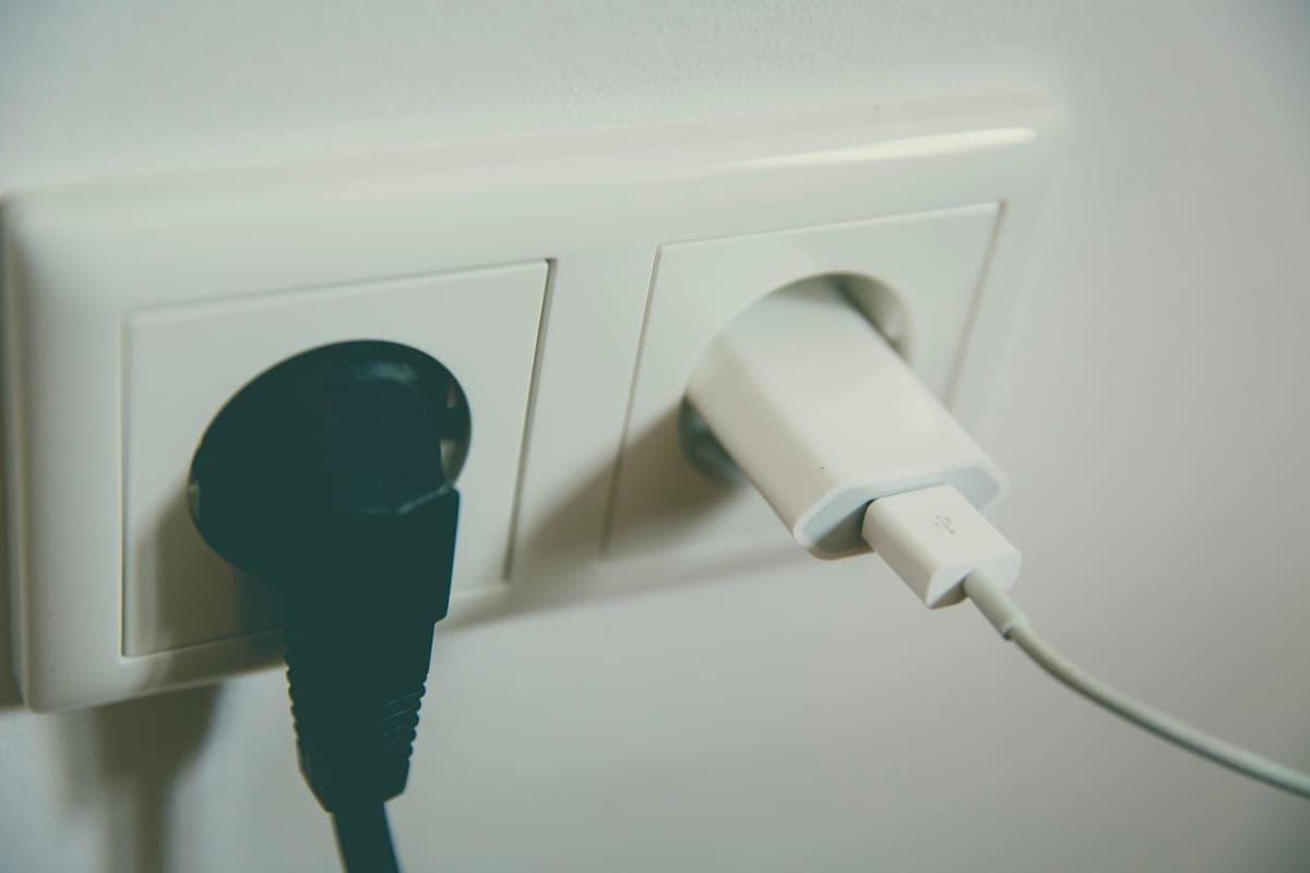 A wall outlet with a lamp cord routed neatly along the baseboard