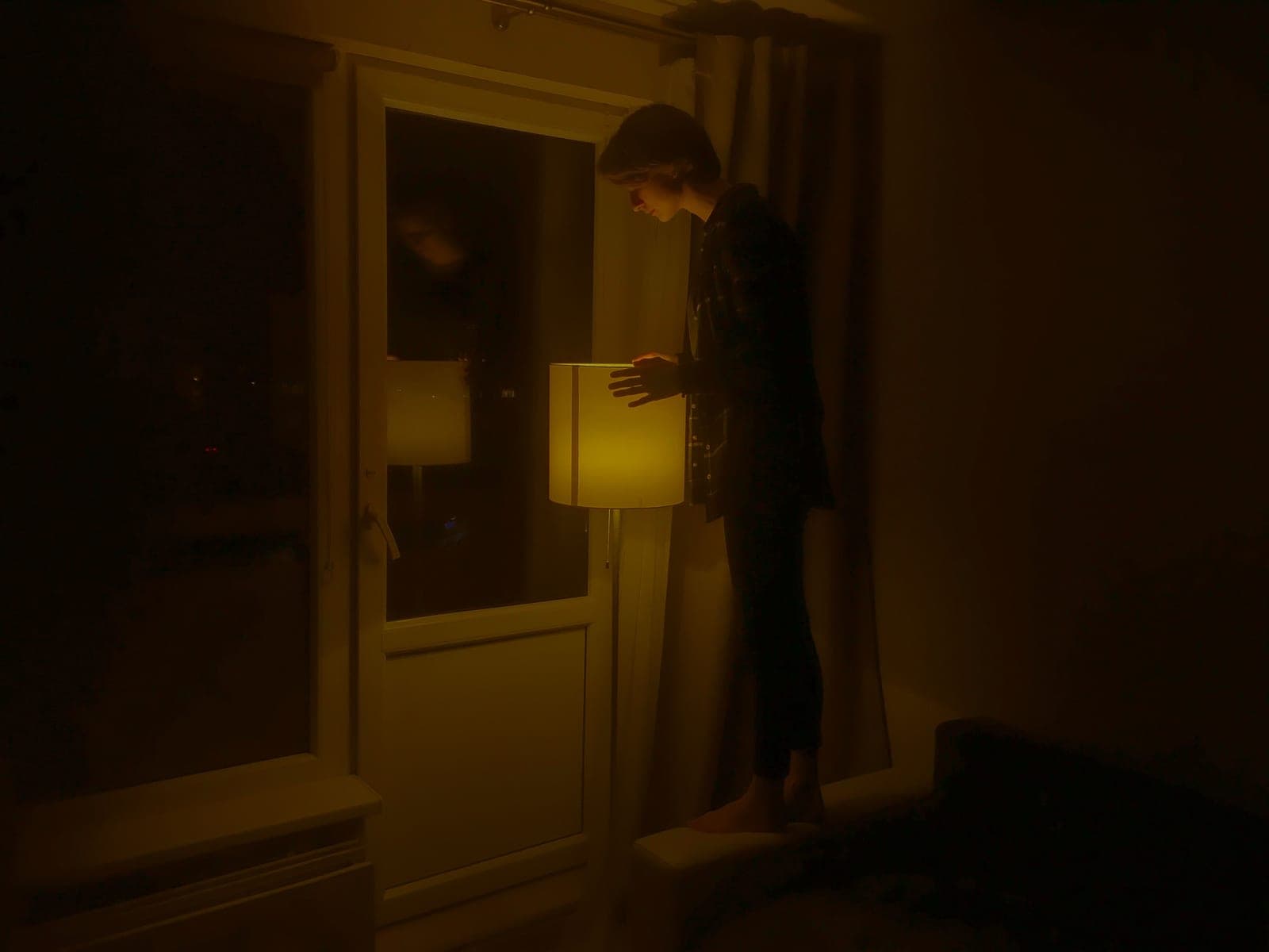 A living room after dark lit by a tall floor lamp bouncing light off the ceiling, with no fixture on the ceiling