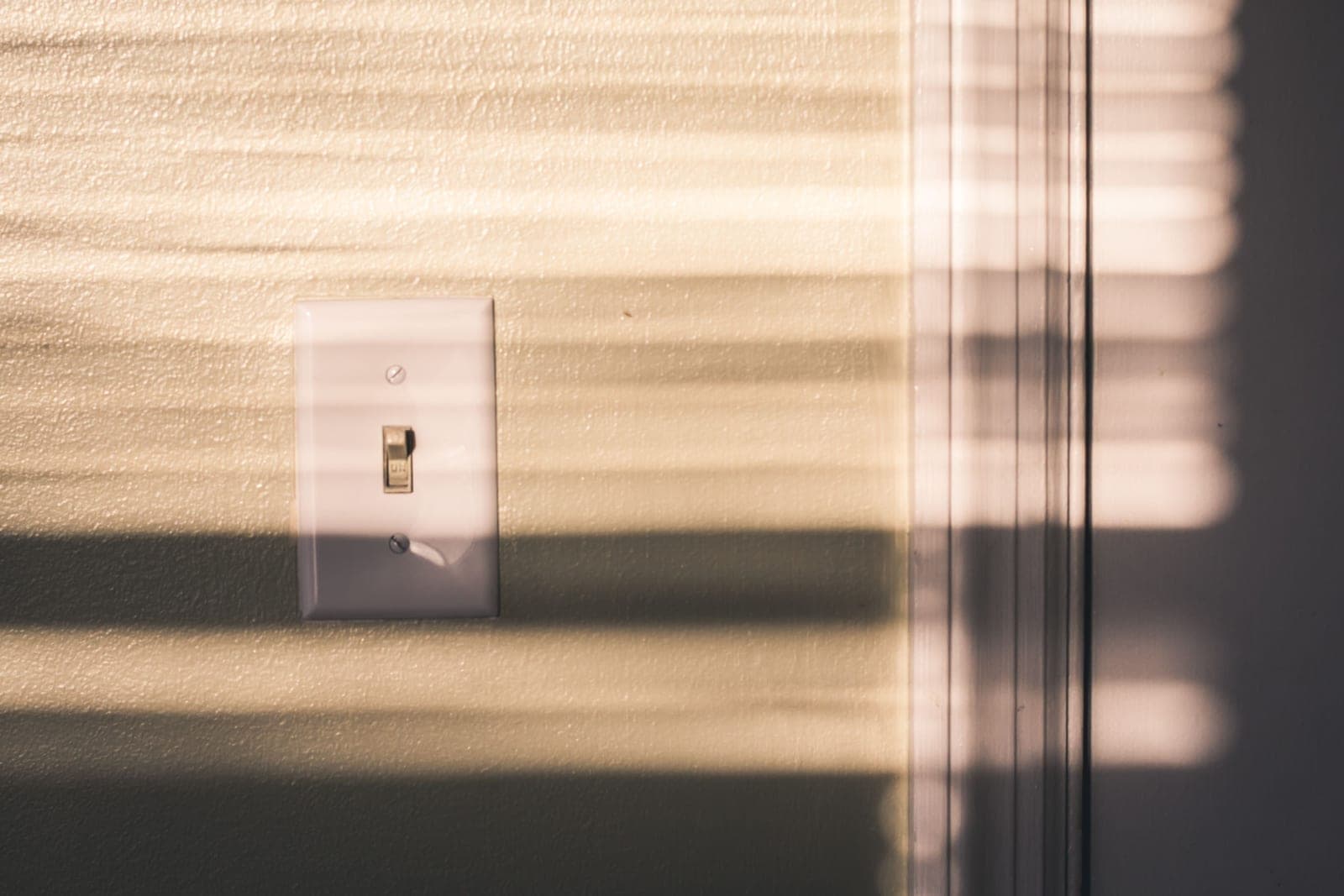A dimmer switch on a wall beside a warmly lit room