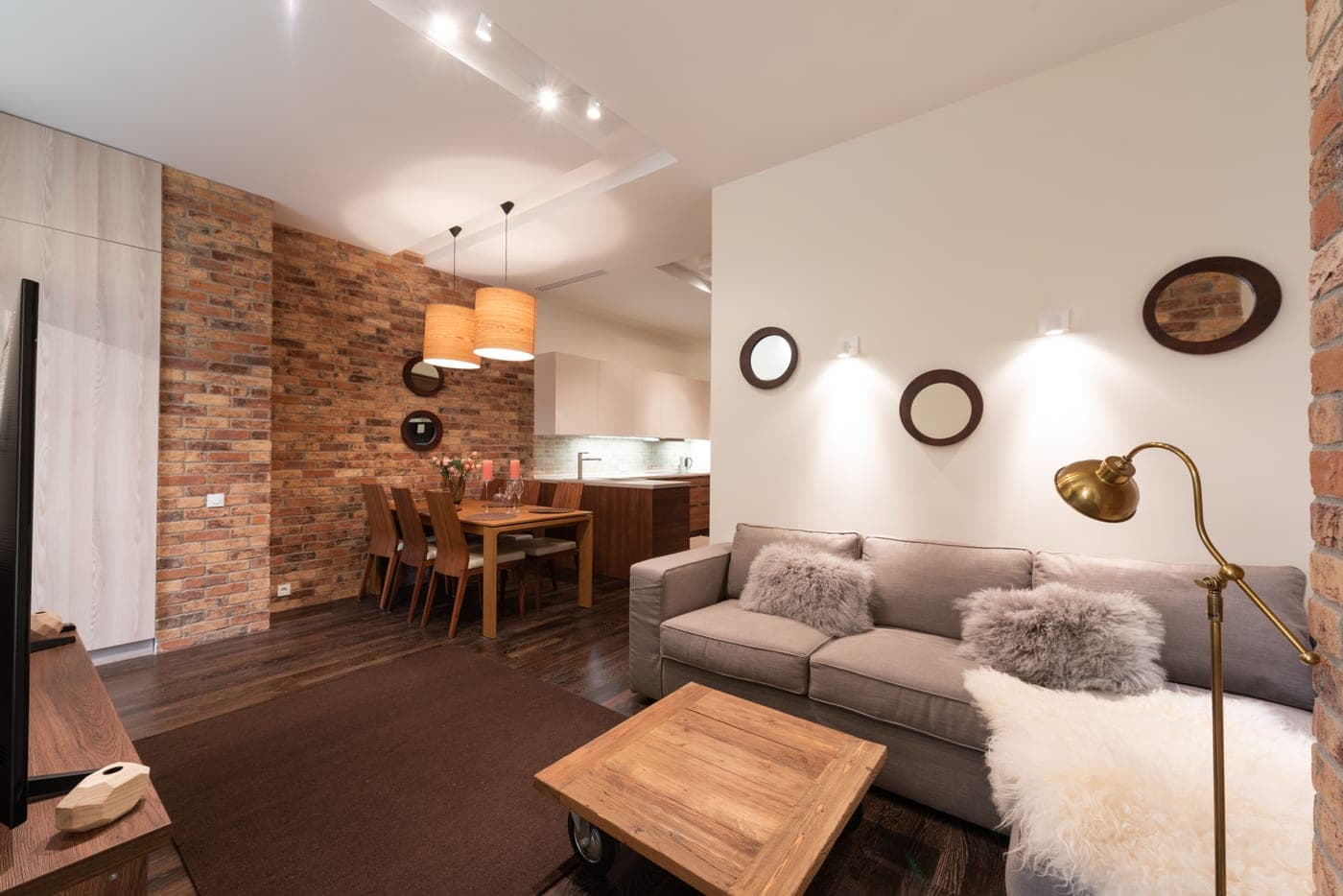 A living room lit after dark by a tall floor lamp bouncing light off the ceiling, with no overhead fixture fitted