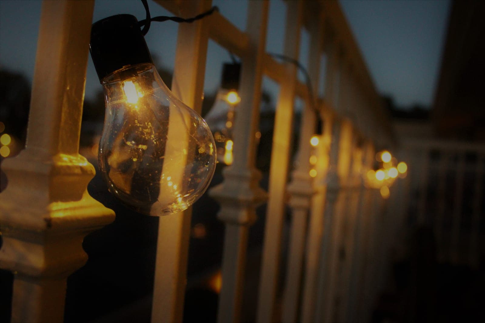 String lights hung across a small balcony at dusk