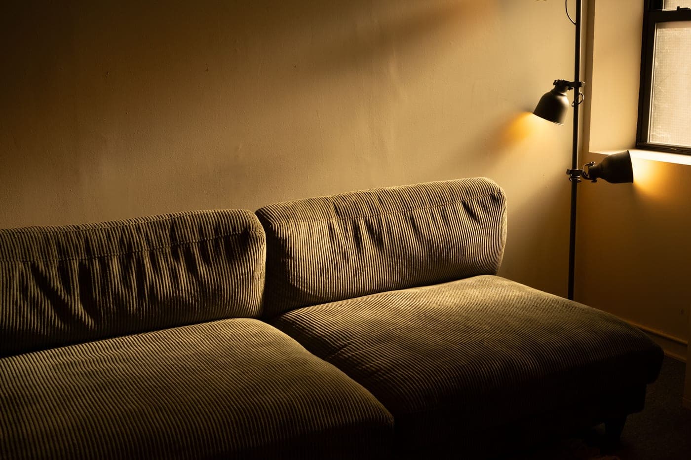 An apartment interior at dusk with lamps lit in several rooms at once
